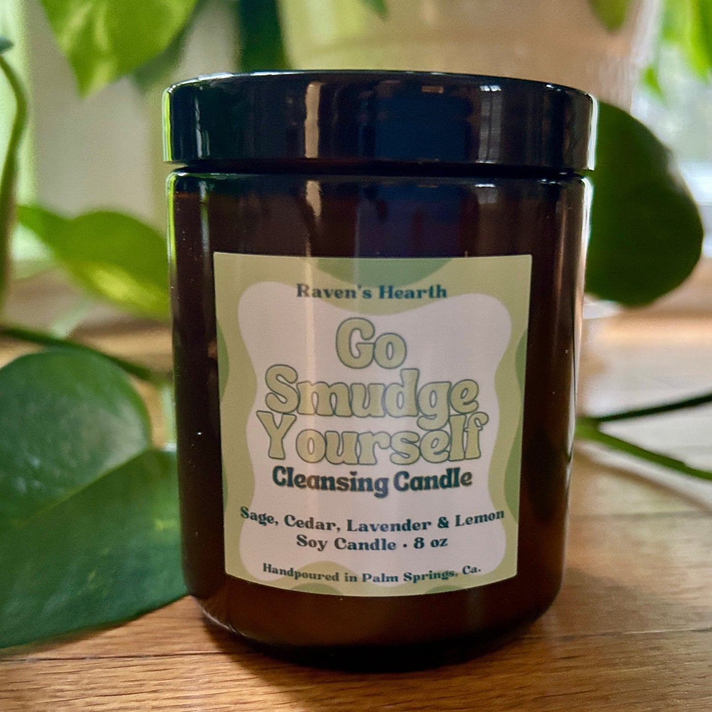 Cleansing candle jar with label on a wooden surface with green leaves in the background