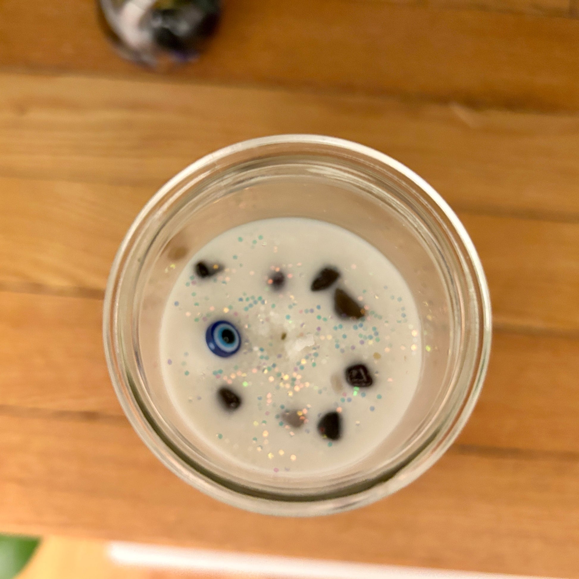 Glass container with a white substance and blue and black specks on a wooden surface