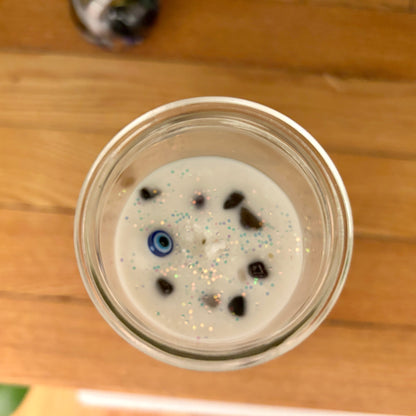 Glass container with a white substance and blue and black specks on a wooden surface