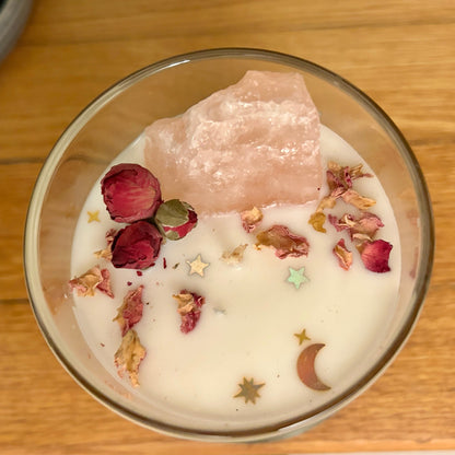 Glass bowl with a pink crystal, dried flowers, and decorative stones on a wooden surface